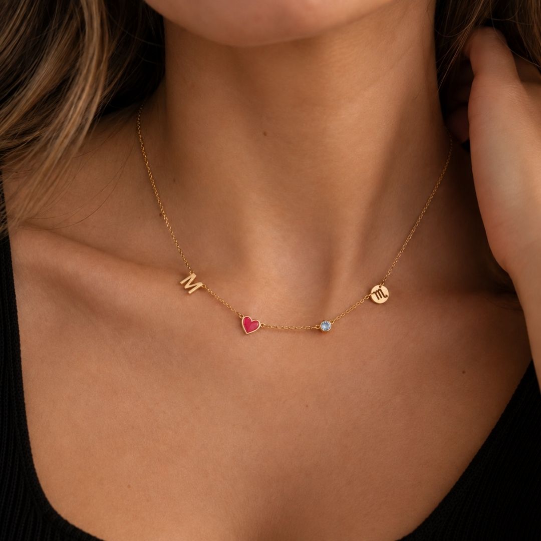 Woman wearing the gold Fable Necklace with an initial, red heart, birthstone and zodiac sign charm